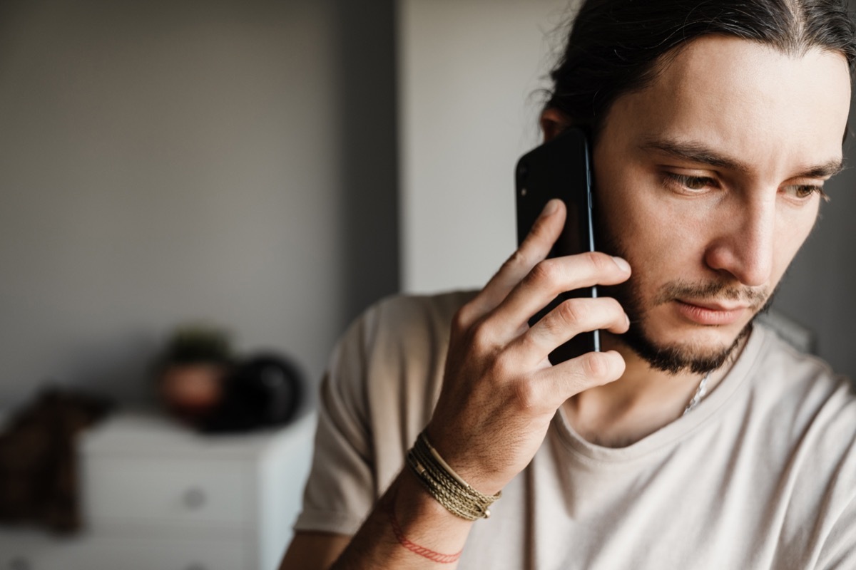 Close up of a concerned mman talking on mobile phone indoors