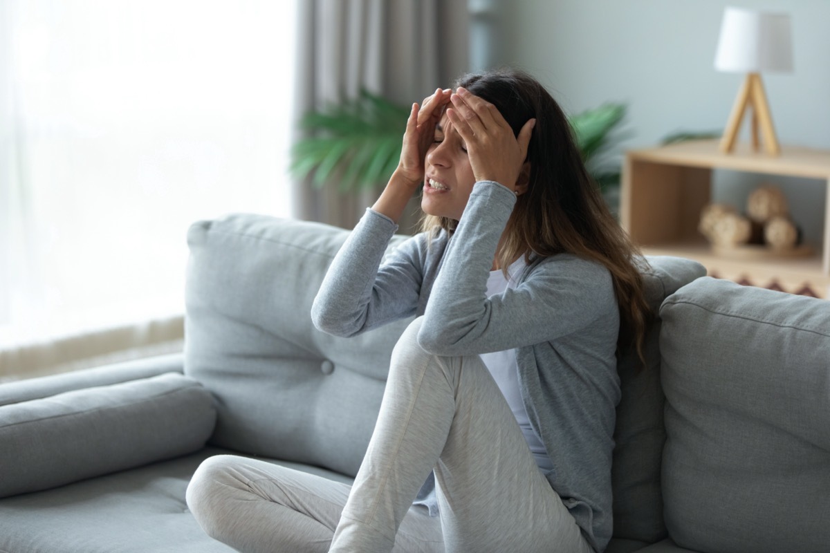 Stressed unhappy woman touching forehead, suffering from strong headache or chronic migraine