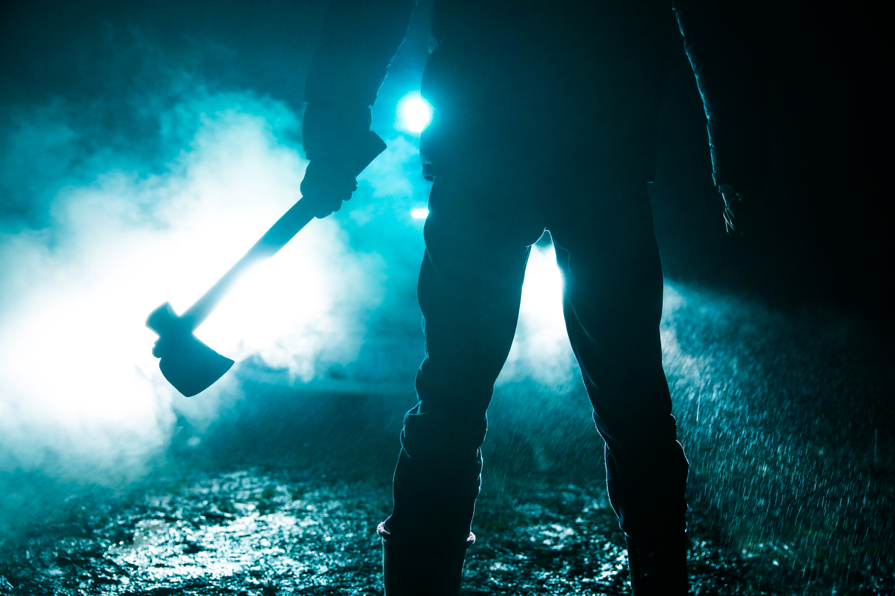 Man holding axe standing in front of car