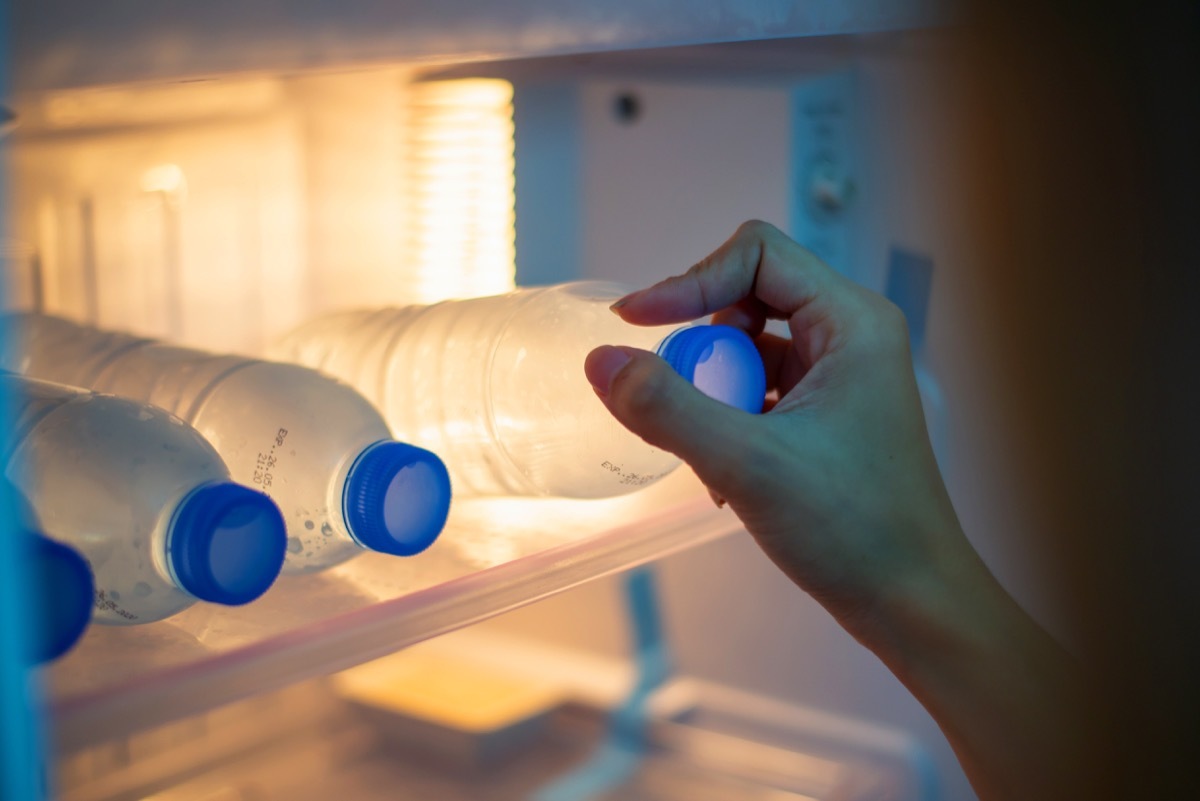 woman grabbing a bottled water in the fridge