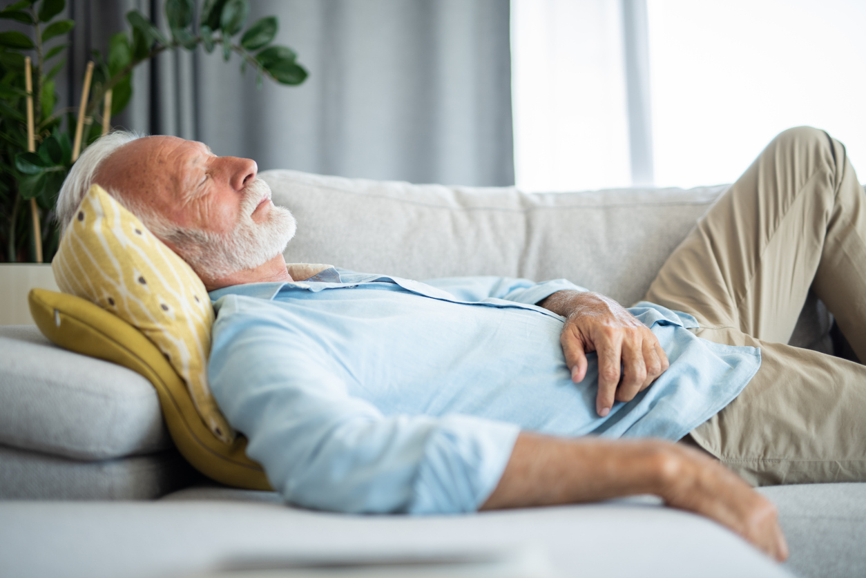 Senior man having a daytime nap on a sofa. 