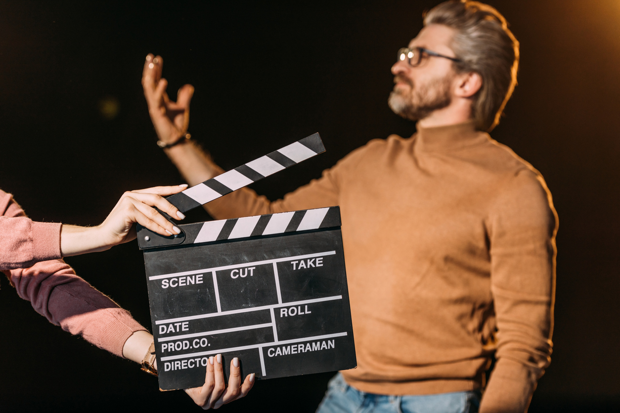 selective focus of mature actor performing role with clapboard in front