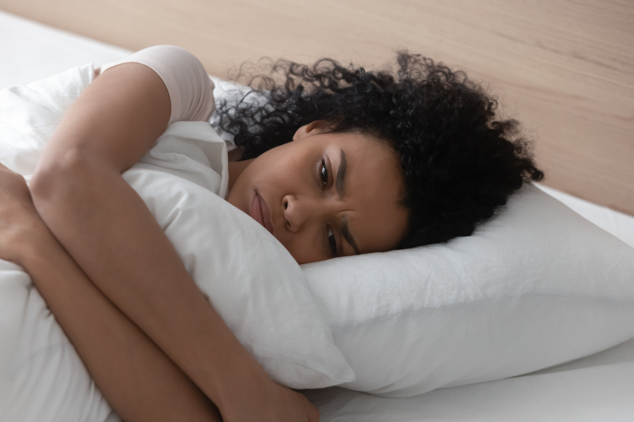 A woman sleeping on her side with a sad look on her face