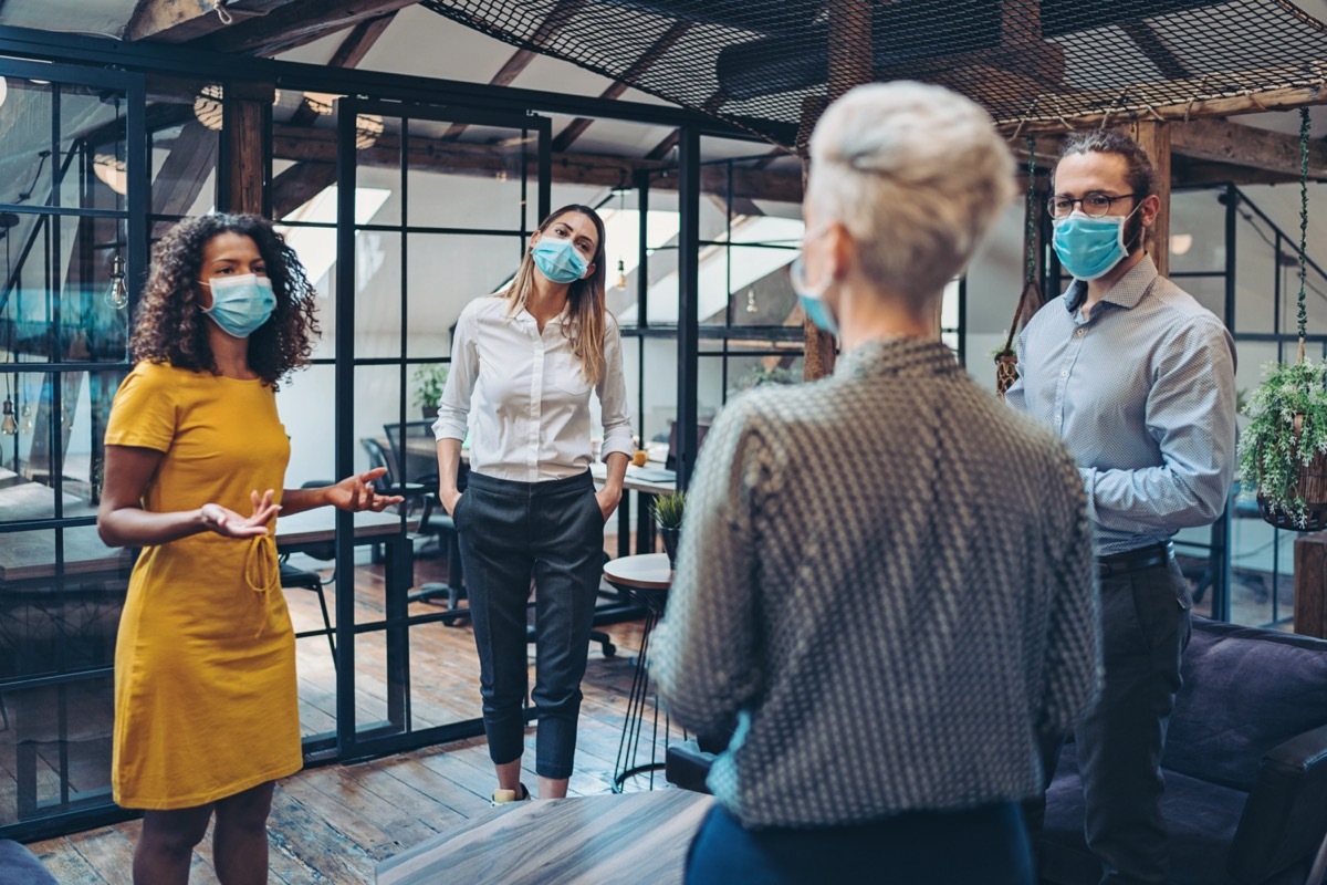 Group of entrepreneurs wearing masks and standing at a distance in the office