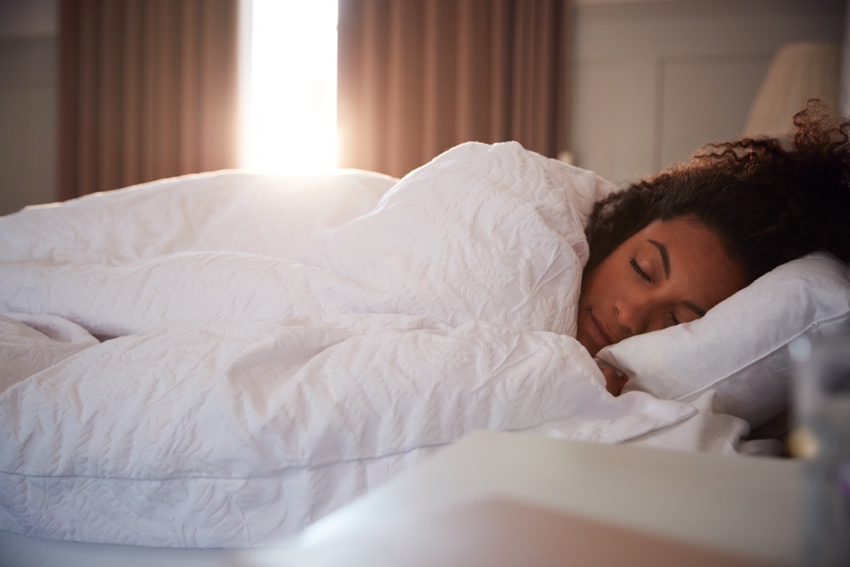 Peaceful Woman Asleep In Bed As Day Break Through Curtains