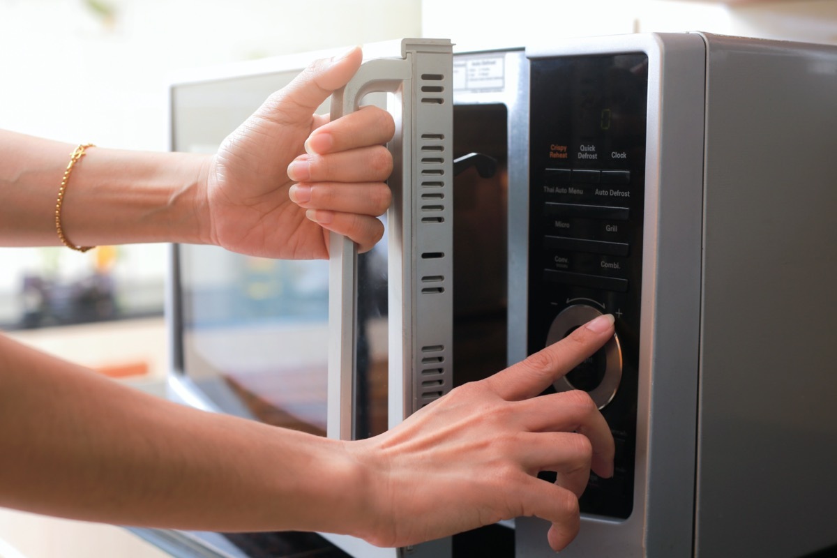 white hand opening door of microwave