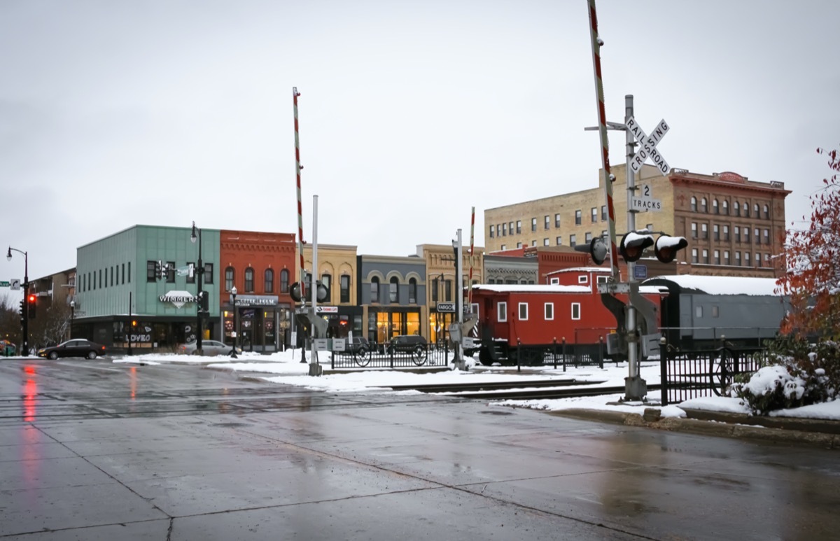 cityscape photo of shop, railroad track, and train in downtown Fargo, North Dakota in the snow