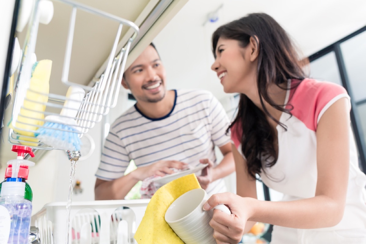 young woman and man taking dishes out of dishwasher