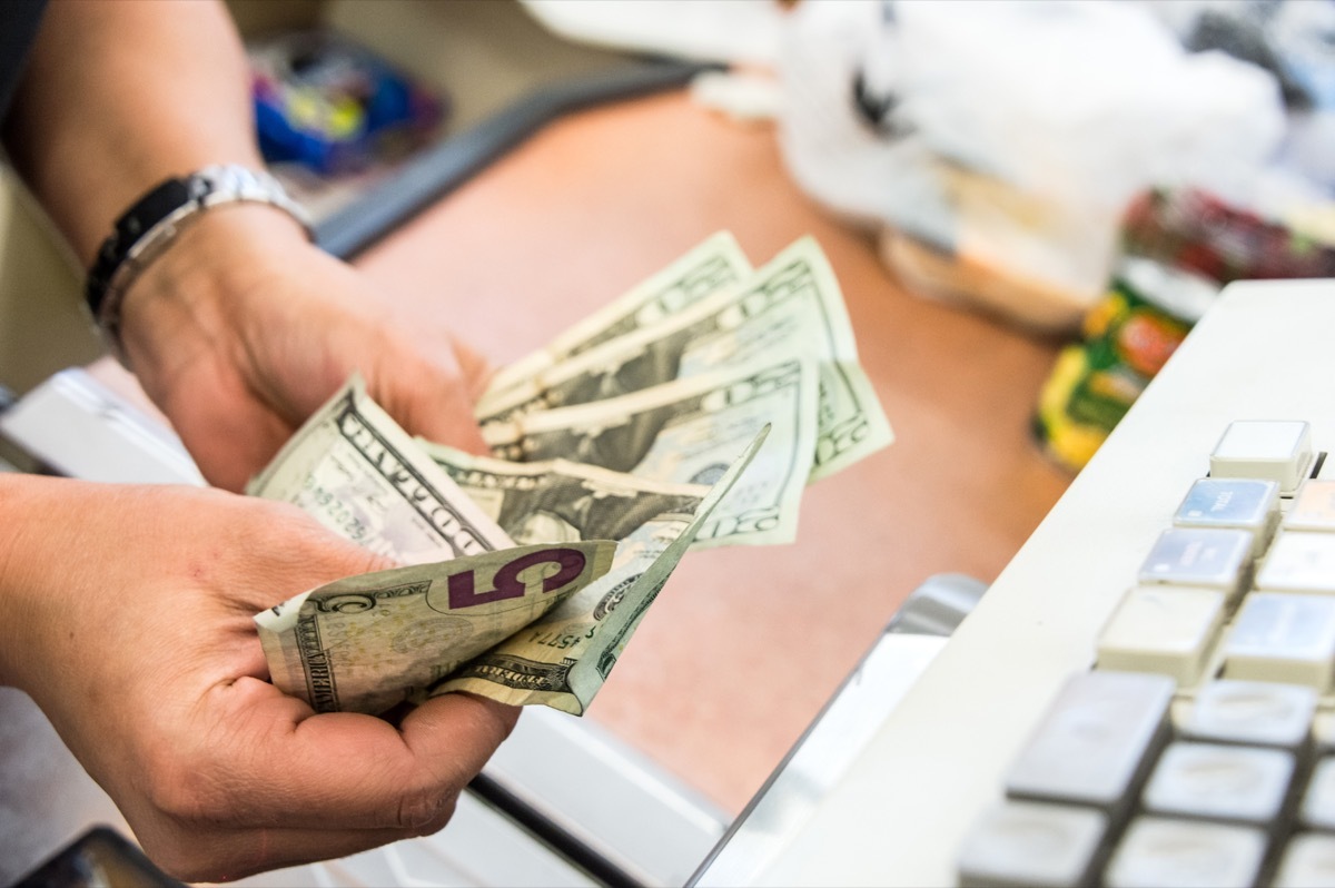 Convenient store female cashier counting the cash at the counter