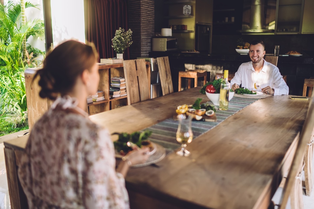 couple sitting very far from each other at large dining table