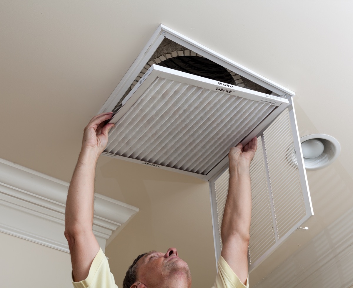 man switching out air filter in his home