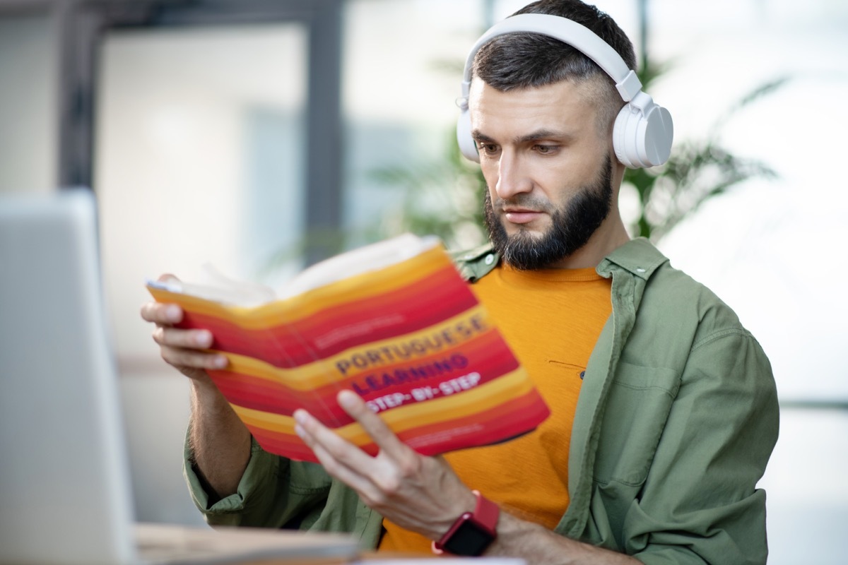 man reading a portuguese language book to learn the language