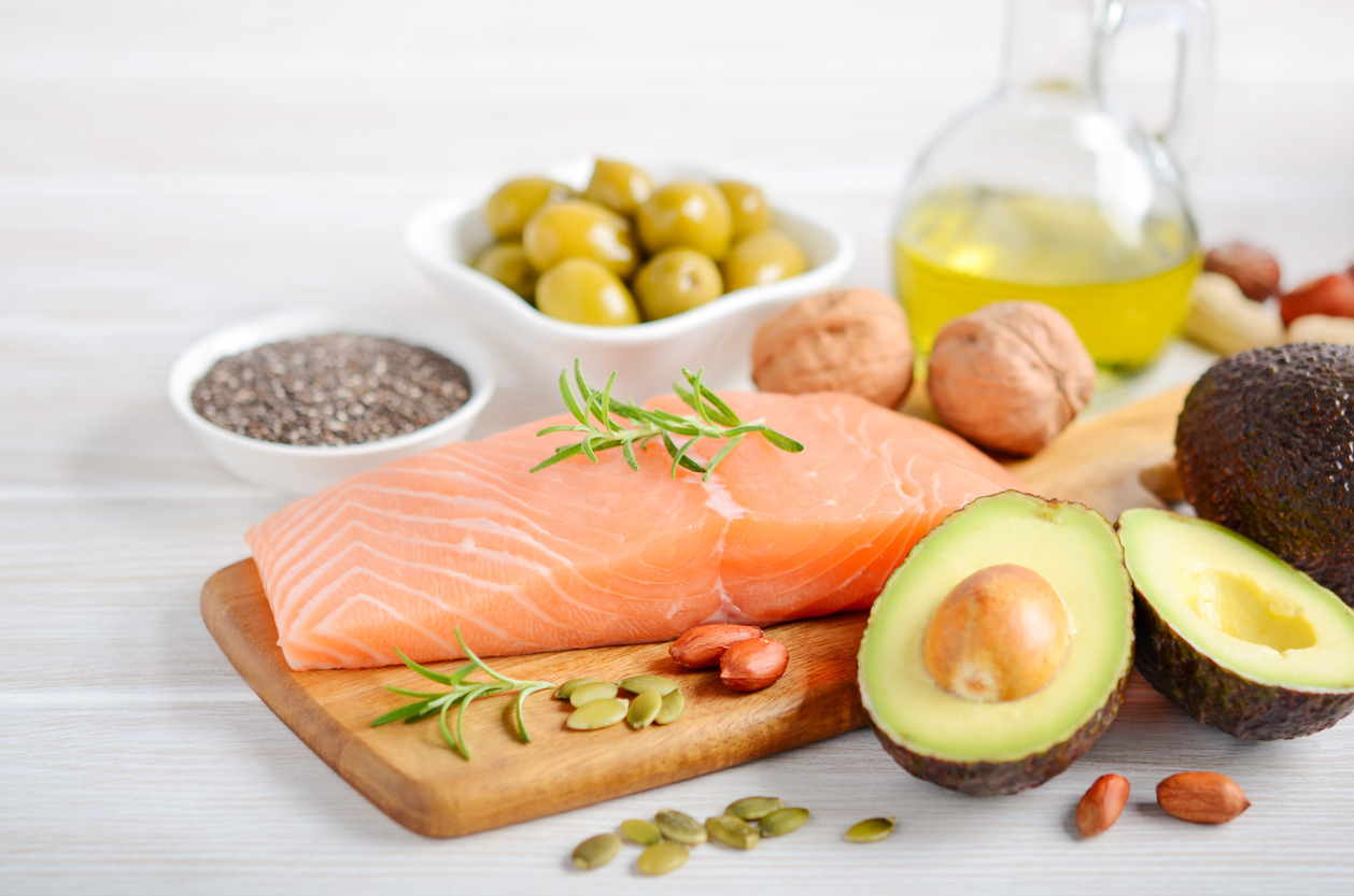 Salmon, avocados, olives, and nuts sitting on a board