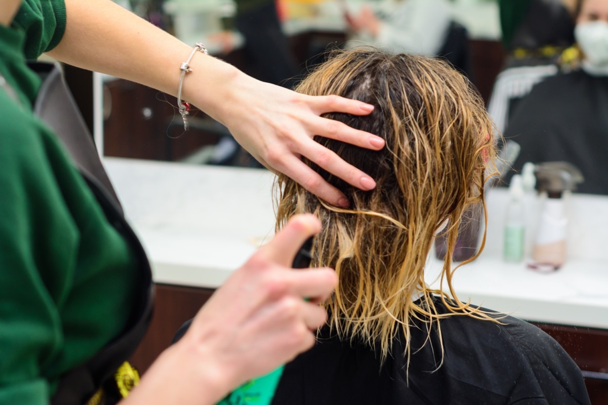 Hairdresser is cutting a woman's wet hair in the saloon.