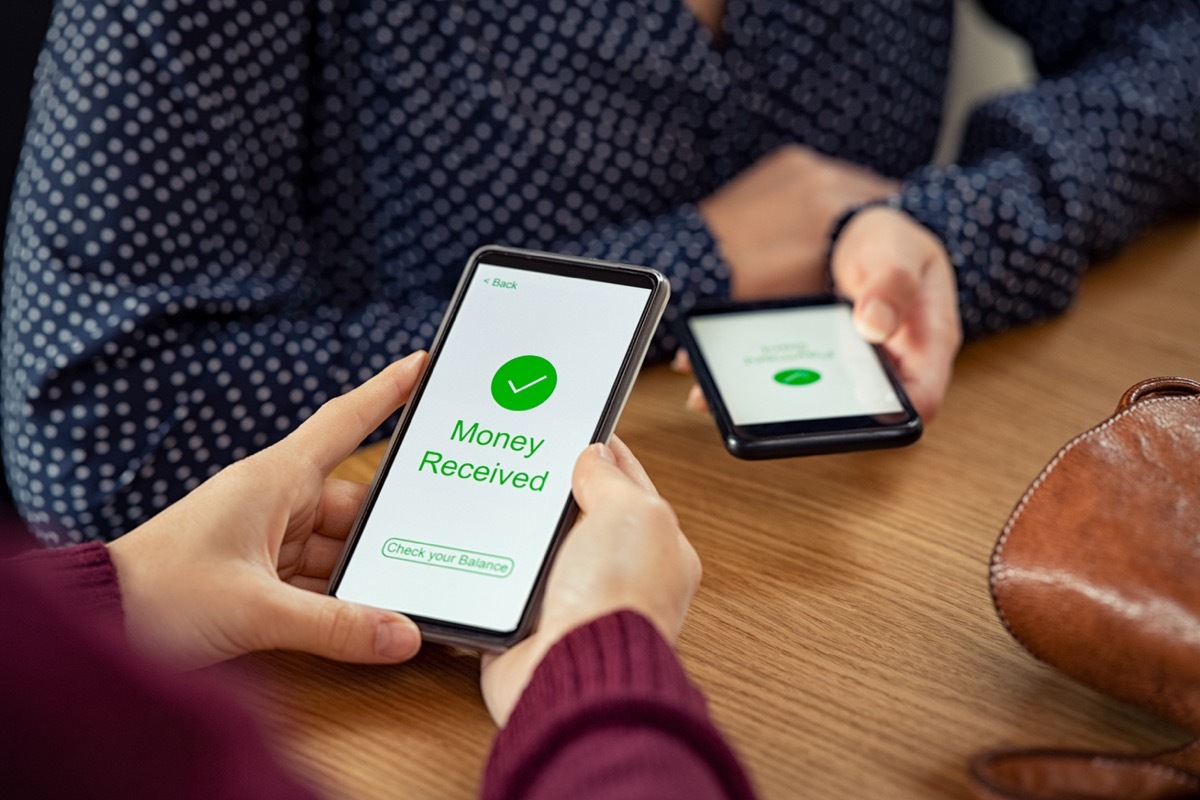 Close up of hands holding mobile phone with application to receive money. 