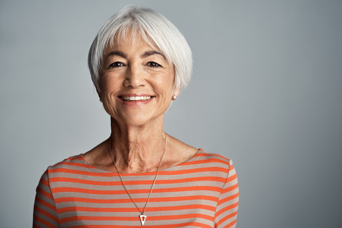 Studio shot of a senior woman standing against a gray background