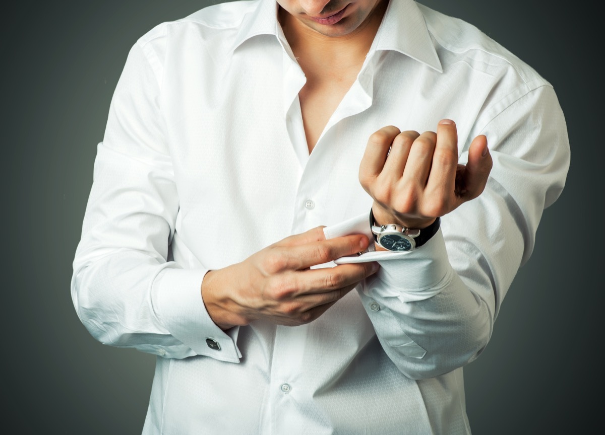 man buttoning a white french cuff shirt