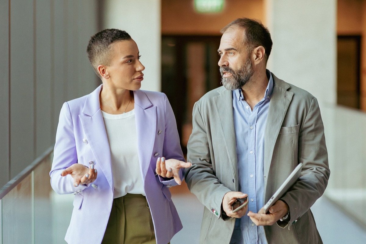 Confident business partners walking down in office building and talking