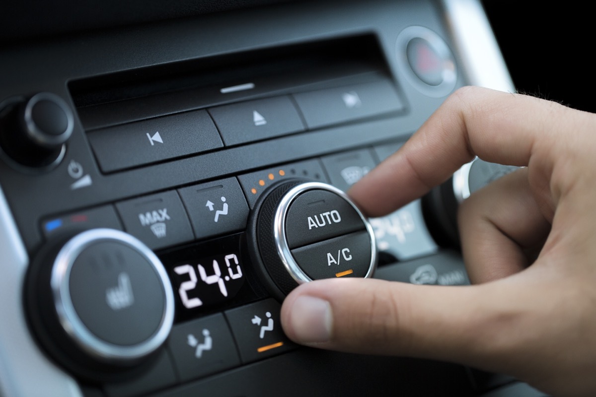 man hand turning on car air conditioning system