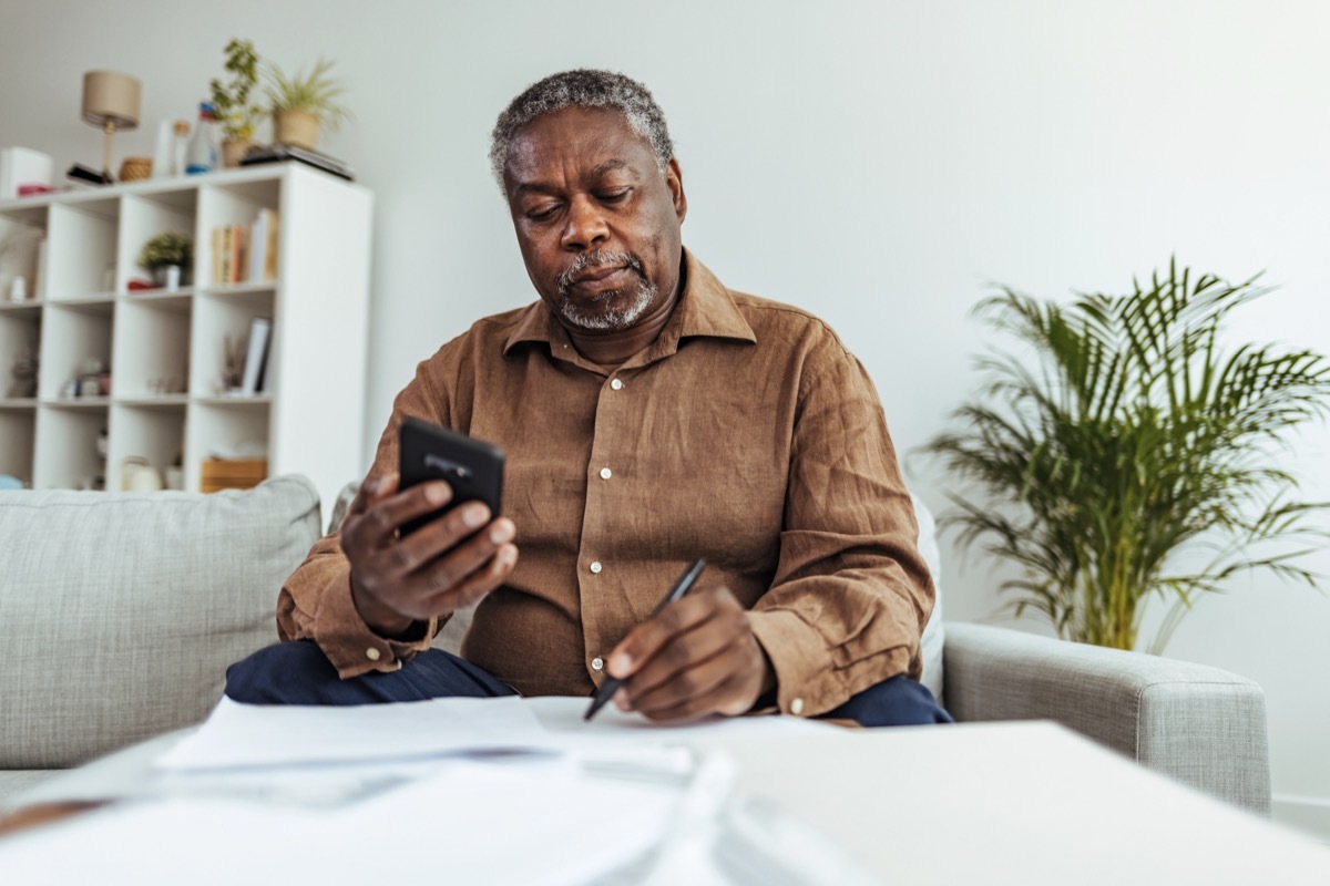 Mature businessman working at home using smart phone