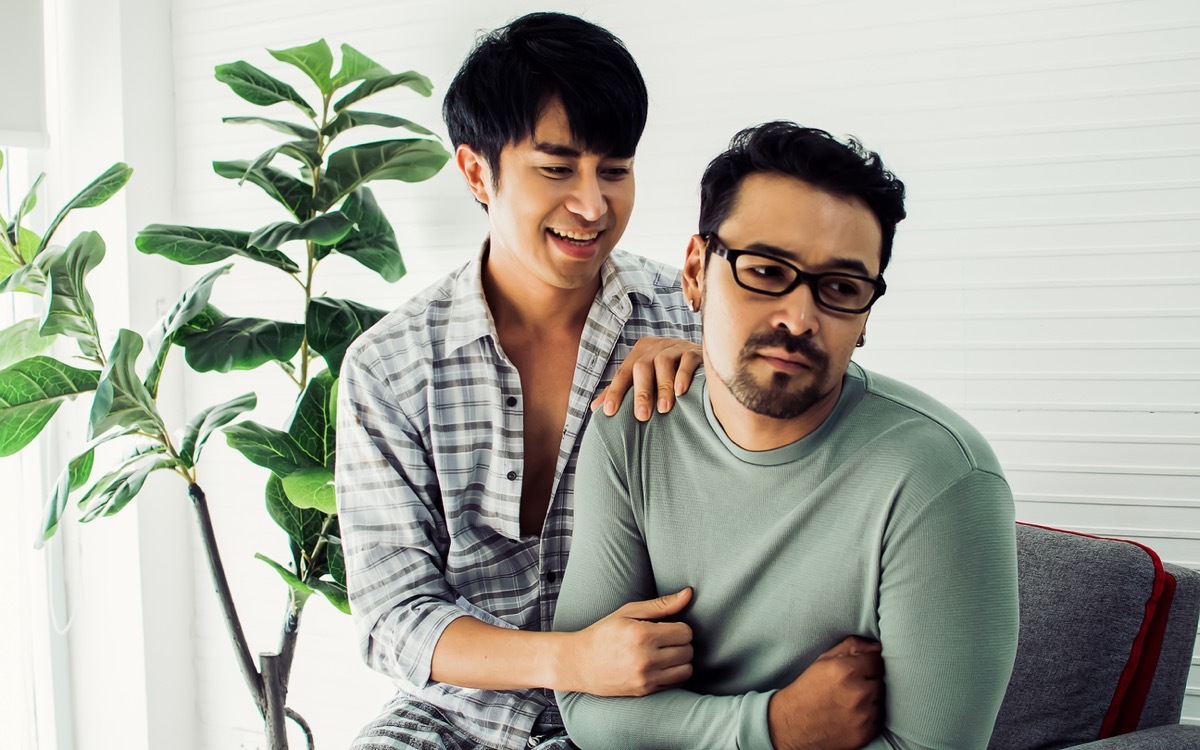 couple wearing pajamas, hugging with happiness and love, reconcile partner while getting sulk, sitting in cozy living room at home, cute posing in Lifestyle Concept