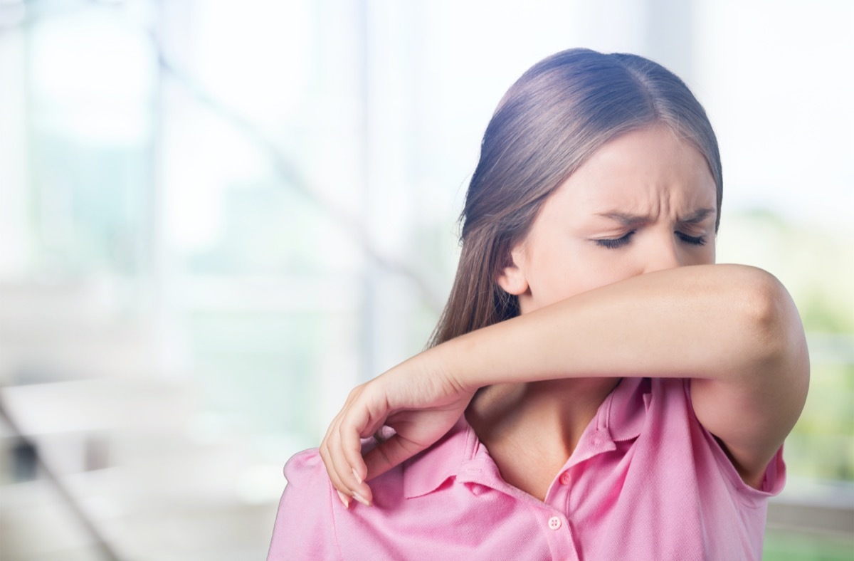 woman sneezing on her elbow.