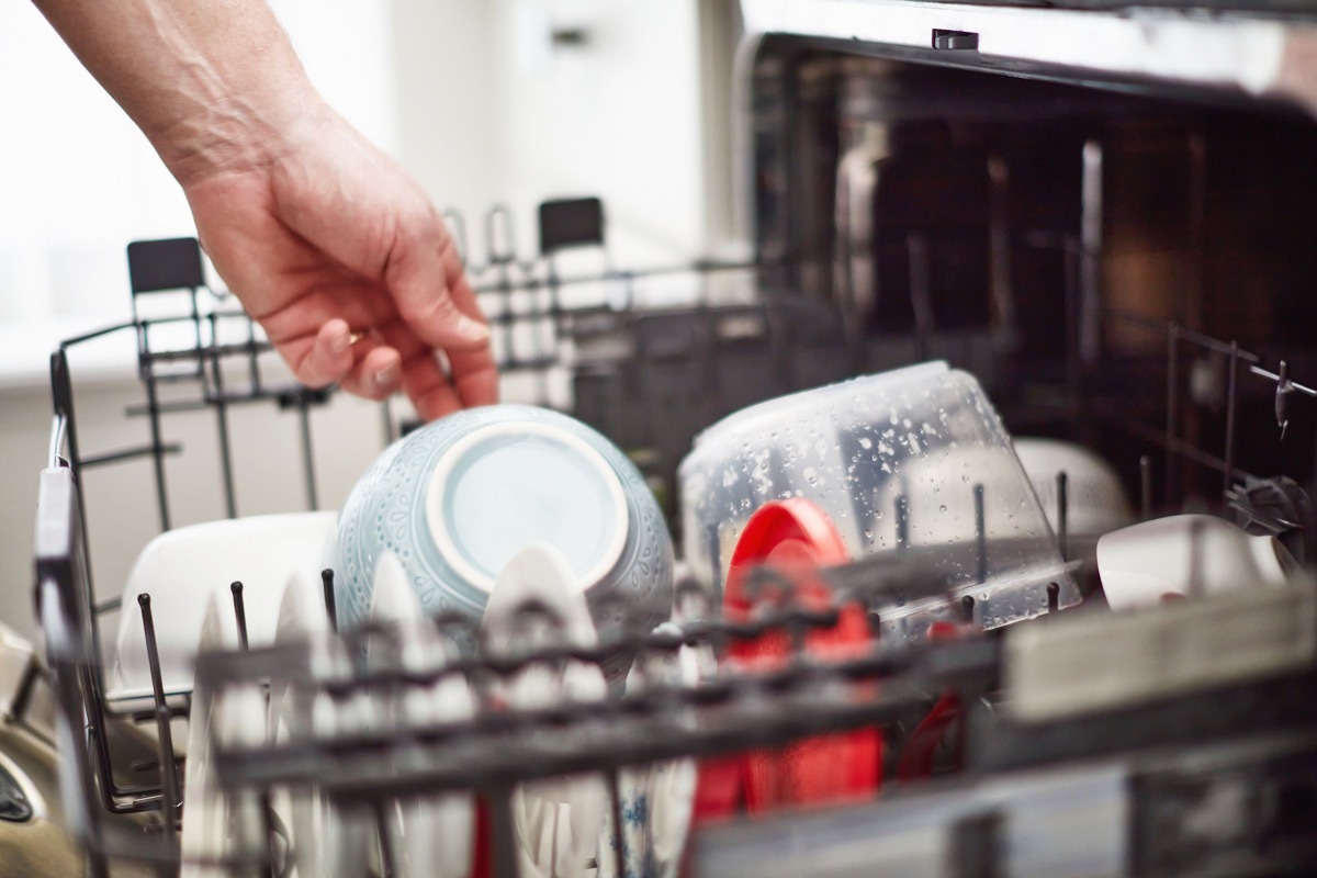 Unrecognizable male unloading dishwasher