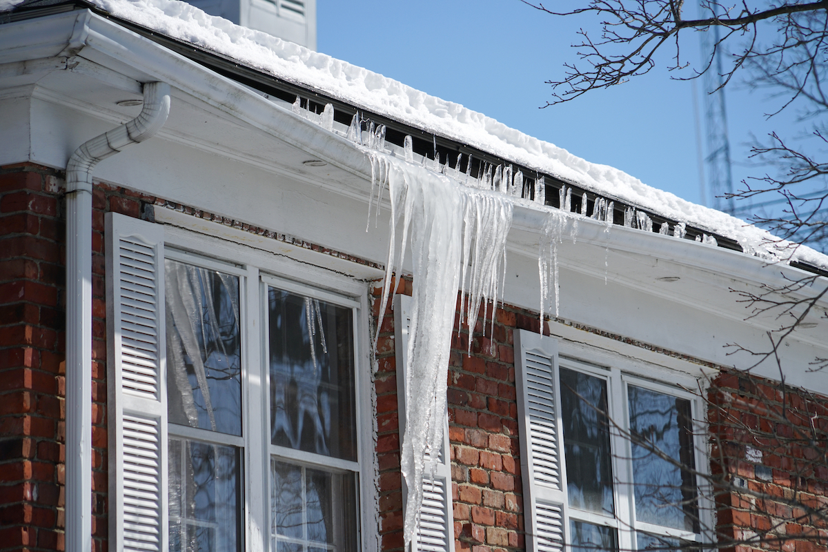 Icicles causing a house's gutters to sag in winter.