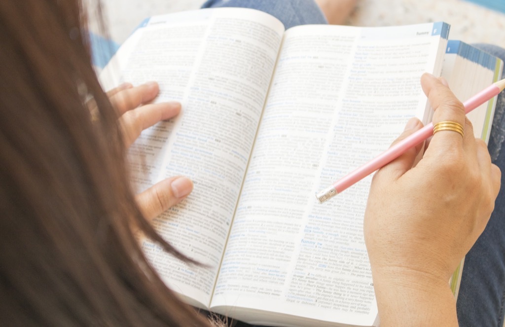 Woman reading and flipping through the dictionary, common word origins