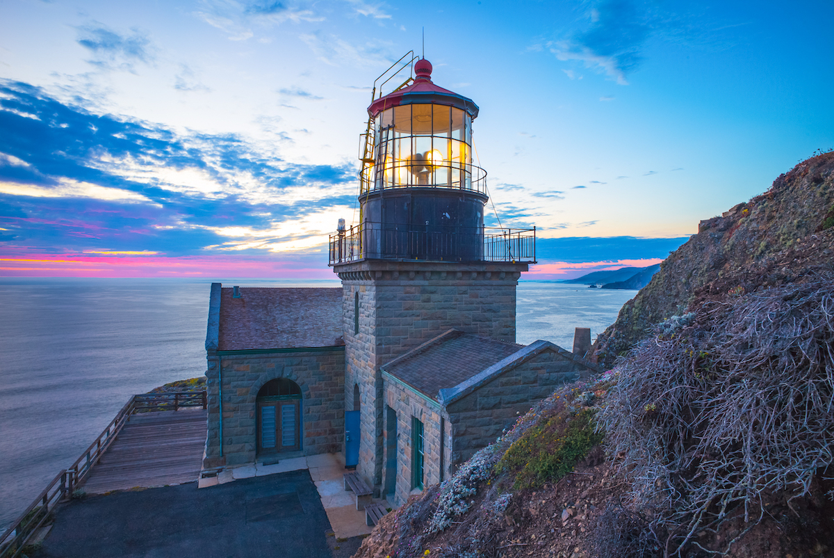 The stone Point Sur Lighthouse in California at sunset.