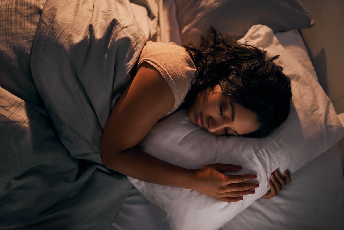 young woman sleeping while holding a pillow in bed