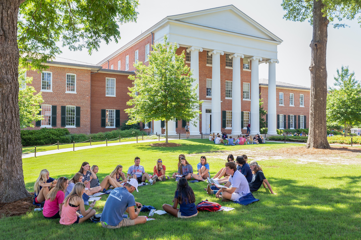 group of students sitting outside in the grass