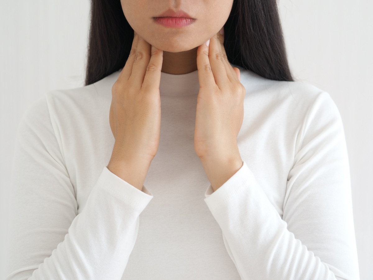 woman touching neck with her hands.