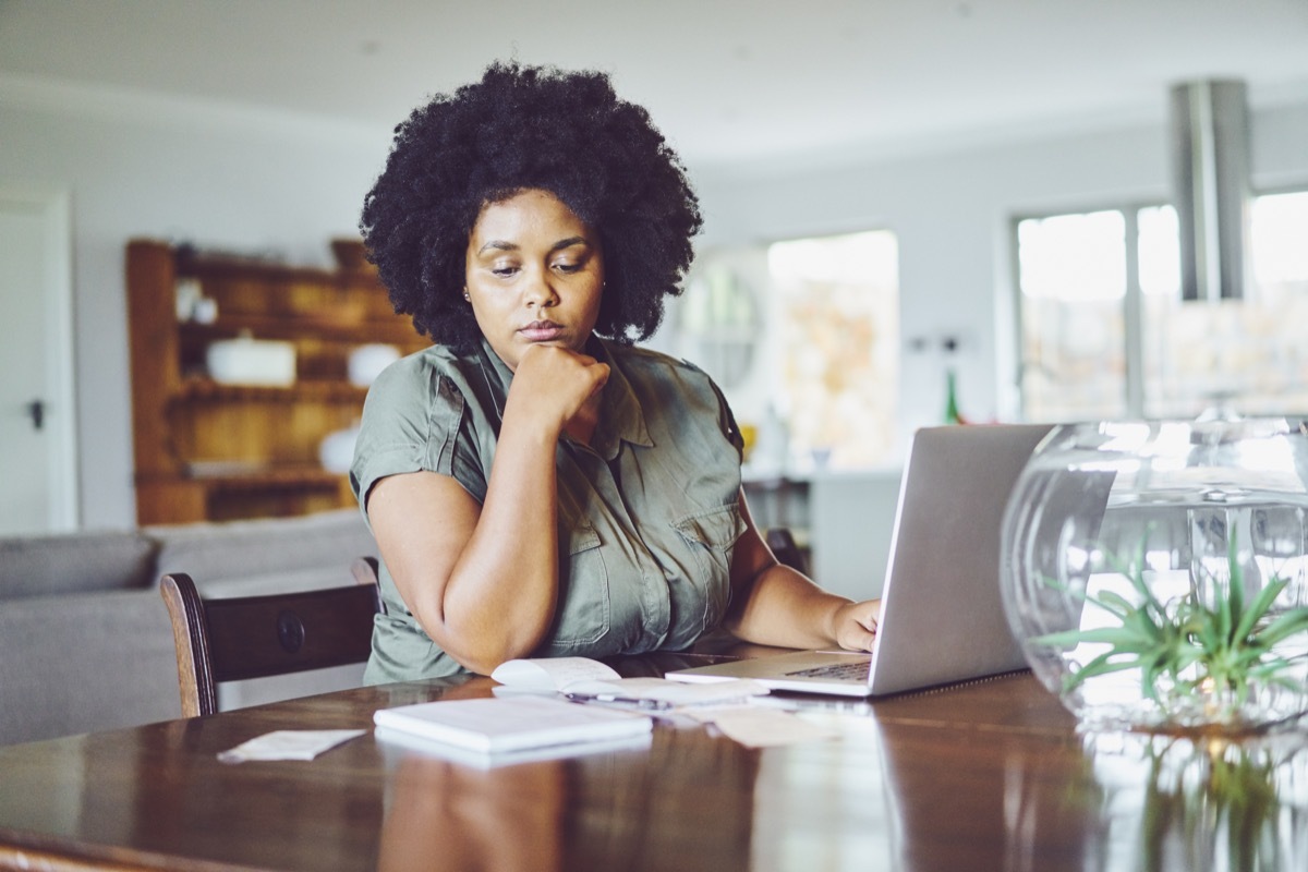 Woman looking concerned while paying bills from home