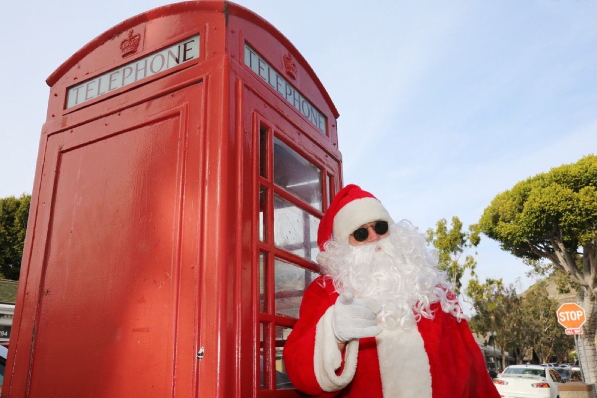 santa stands with sunglasses on at london phone booth