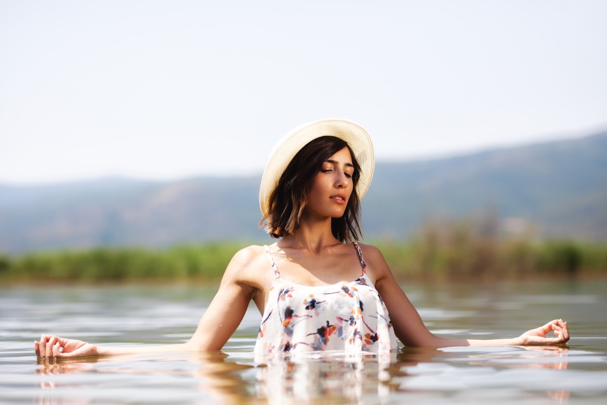 Woman Meditating in Body of Water