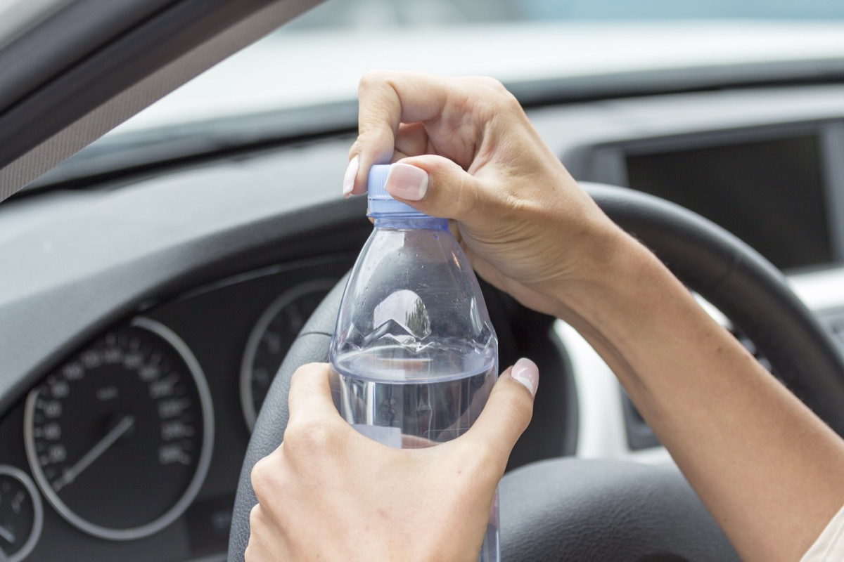 person with painted nails opening plastic water bottle