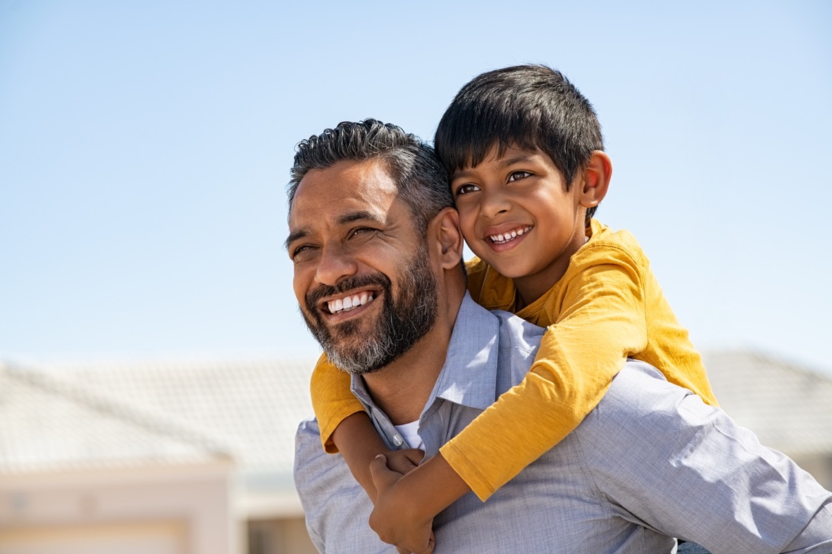 Smiling young dad giving piggyback ride to son on street