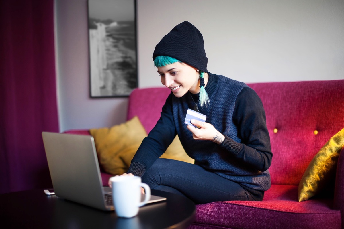 Young woman with blue hair shopping online in her living room