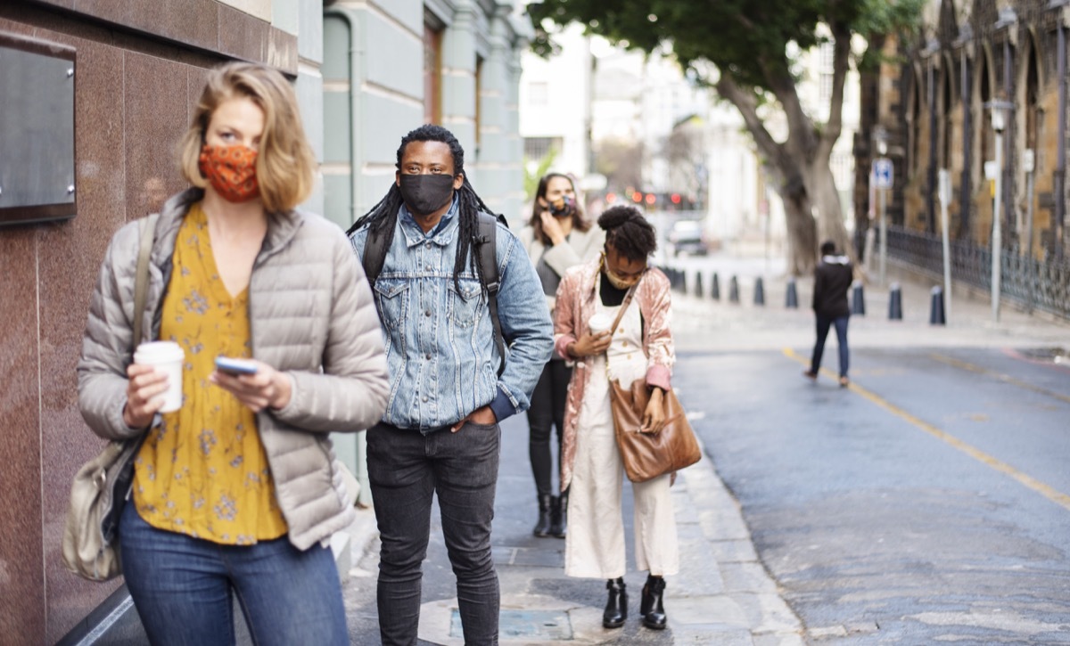 Group of people in face masks social distancing on a city sidewalk