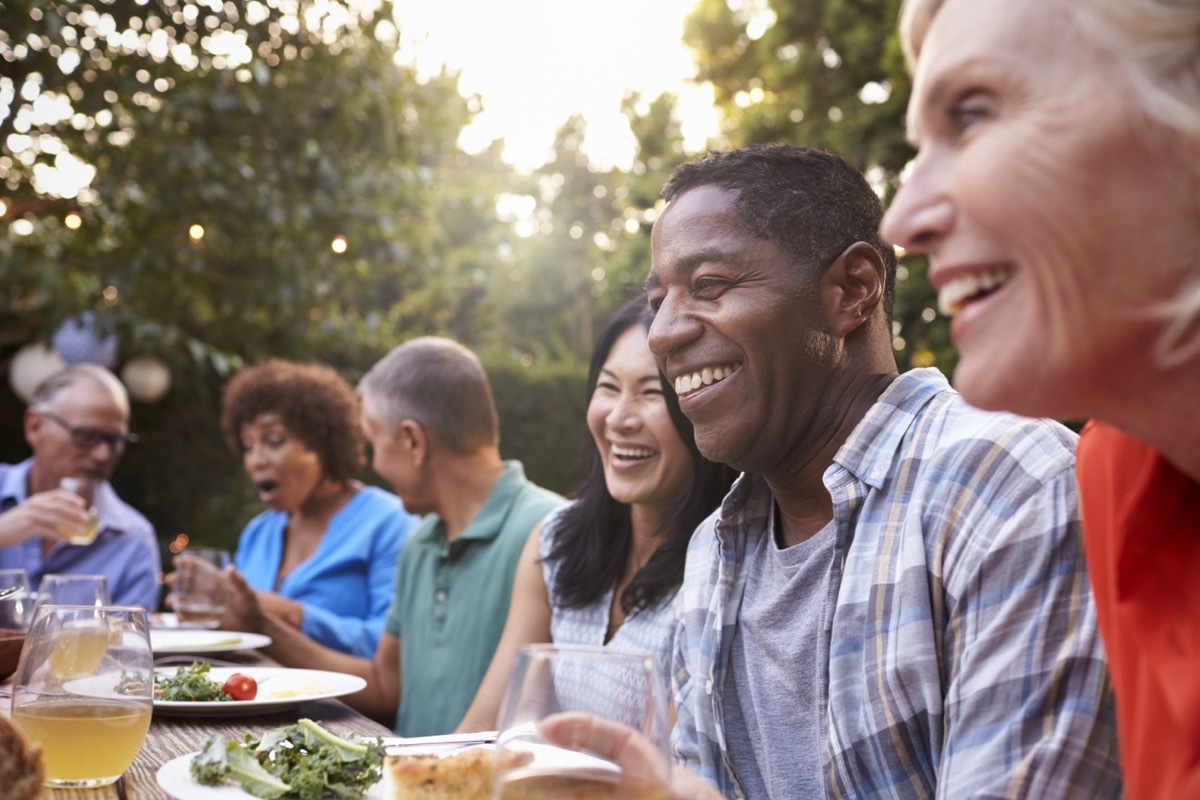 middle aged friends eating a meal outside during the day