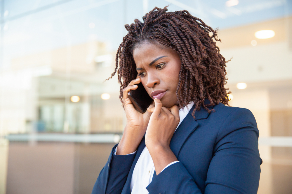 A young woman taking a phone call with a concerned look on her face