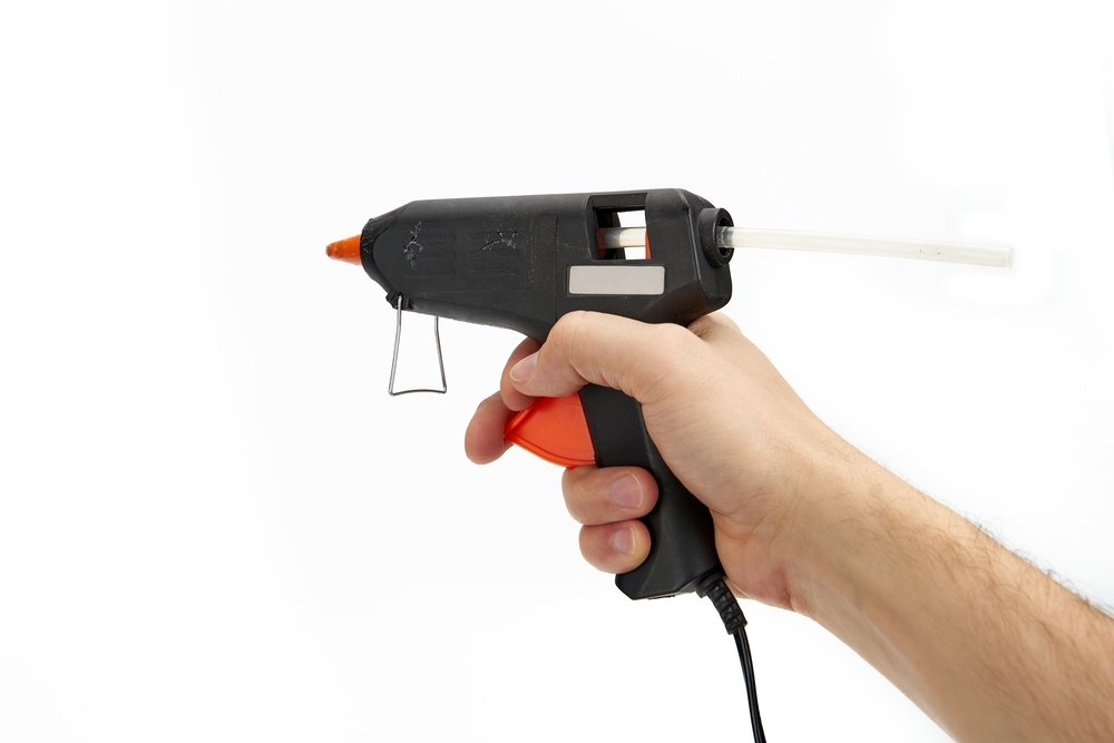 Close-up of a hand using a hot glue gun