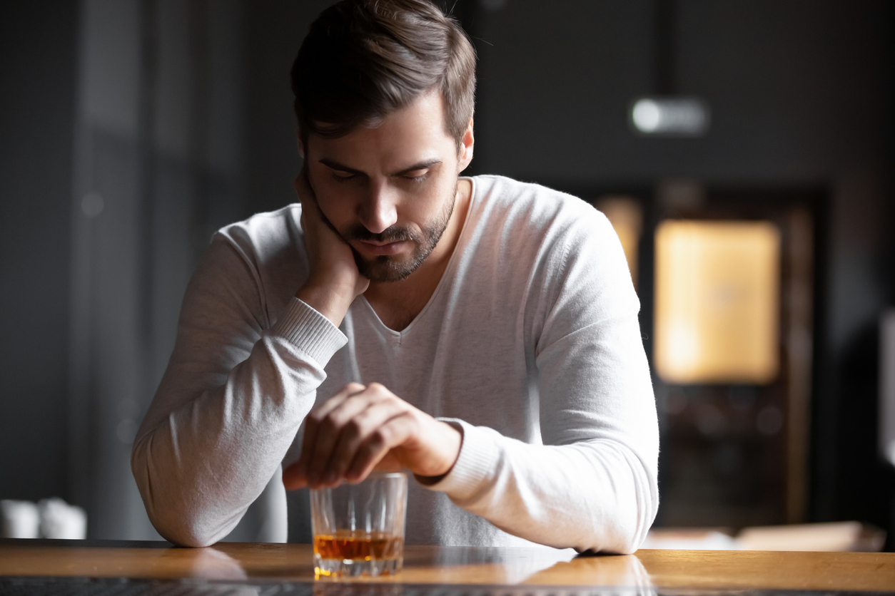 Man sitting at bar counter with glass.