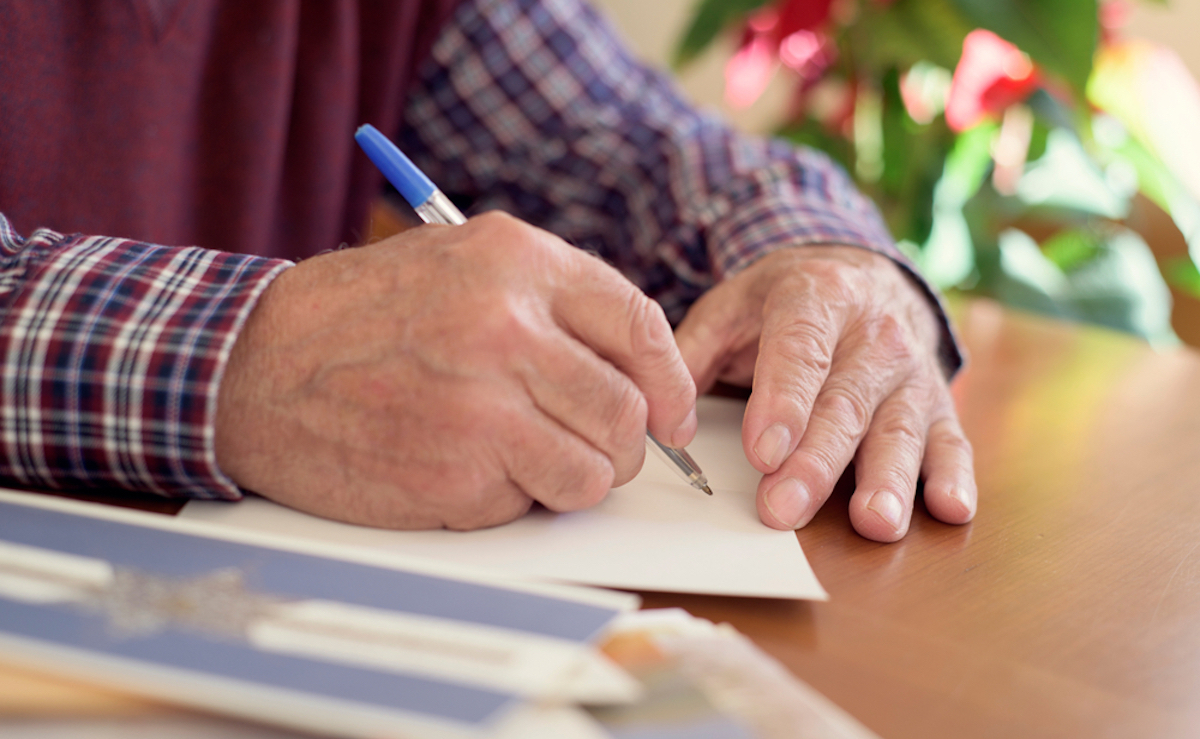 closeup of man's hand writing card