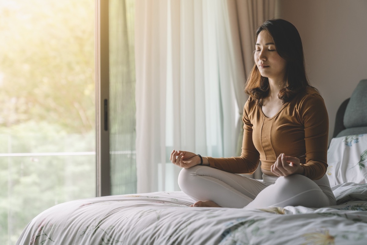 woman meditating at bedroom