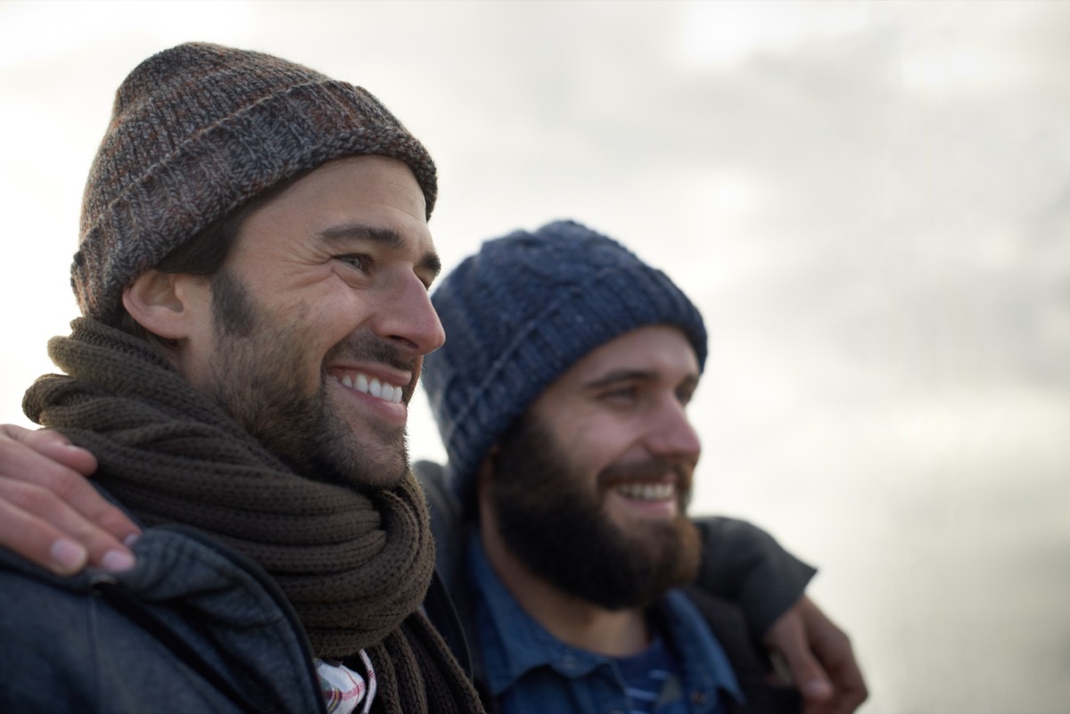 Two handsome young men standing on the beach on a cool morning