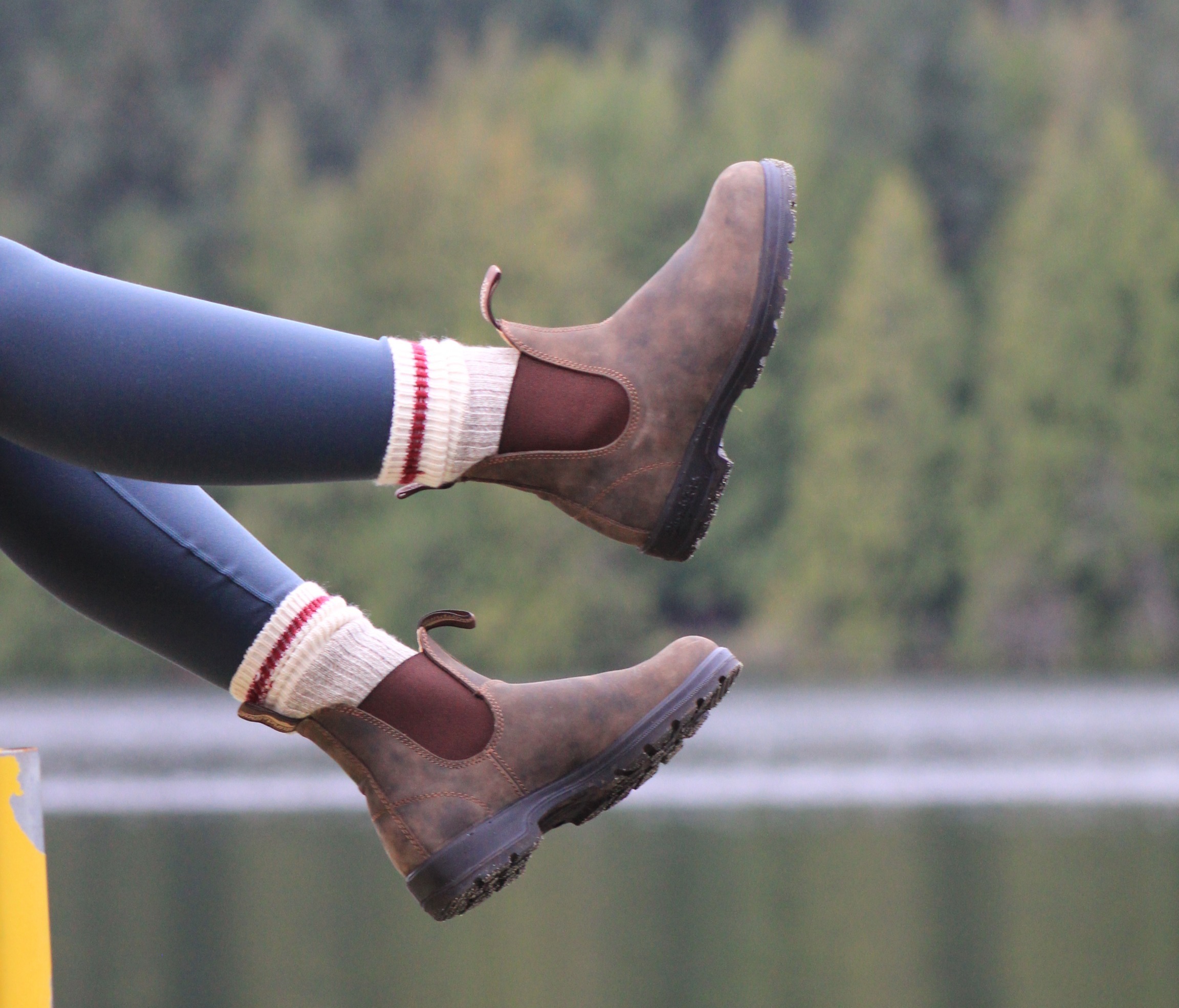 woman wearing blundstone boots sitting by a lake