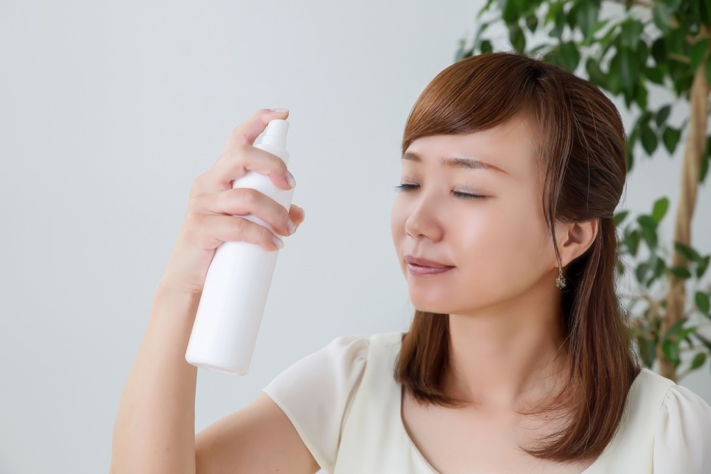 Woman spritzing her face with a facial spray