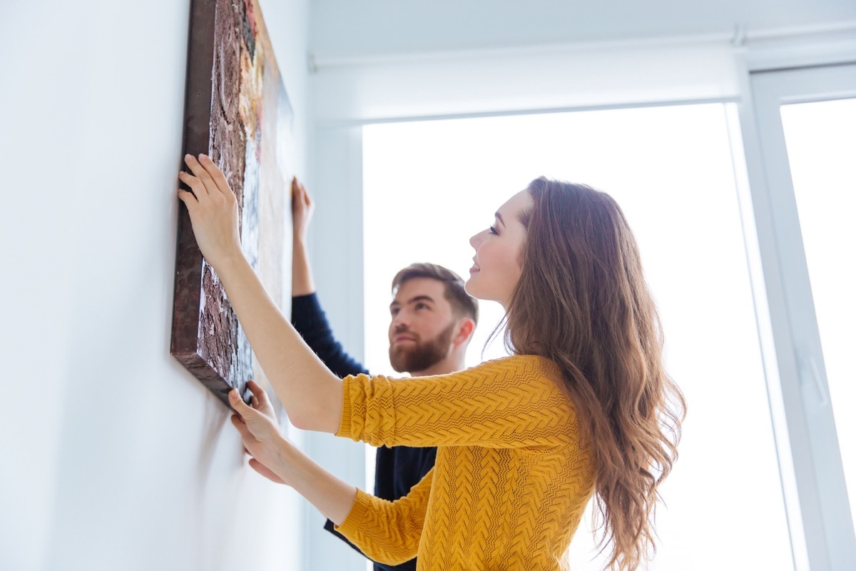 Couple hanging a piece of art in their home